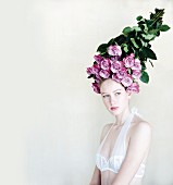 Junge Frau mit einem Strauß lila Rosen auf dem Kopf