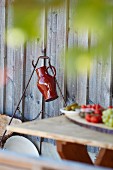 Red jug hanging on metal frame against wooden wall; lunch on table in blurred foreground
