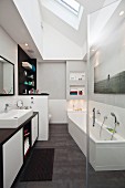 Washstand and fitted bathtub below skylight in renovated bathroom