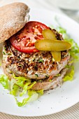 A pork burger with chillis, tomatoes and gherkins