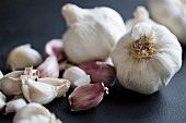 Garlic bulbs and individual garlic cloves on a black surface