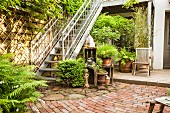 Begrünter Terrassenplatz mit verzinkter Balkon-Außentreppe und Topfpflanzen auf Natursteinboden