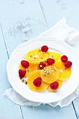 Orange slices topped with raspberries and chopped pistachio nuts