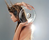 Frau mit wehenden Haaren hält Glasschale