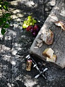 Rustikale Holzplatte mit Käse und Brotstücken auf Steinuntergrund