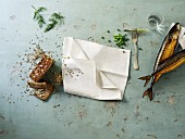 an arrangement of smoked mackerel, wholemeal bread and a white napkin
