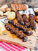 Grilled skewers and white bread on a chopping board