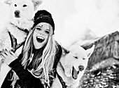 A young woman wearing a faux fur coat and a hat with husky dogs (black and white shot)