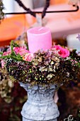 Wreath of hydrangeas, roses and elderberries encircling pink candle on candlestick