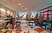 Painter's studio in loft with colourful modern paintings and pictures on wall and large desk in foreground