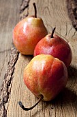 Three fresh red pears on a wooden surface