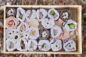 Flowers in white cloth bags, in a wooden box filled with rice