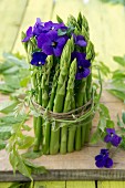 Table decoration made from green asparagus and tufted pansies