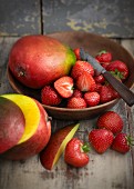 Mangoes and strawberries in a wooden bowl