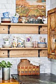 Verschiedene Tassen mit Untertellern auf Holzregal in rustikaler Küchenecke