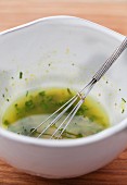 Dressing with fresh herbs and a whisk in a bowl