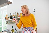 A woman holding a glass of wine in a kitchen