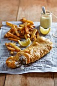 Fish and chips with lemon aioli on a piece of newspaper