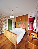 Double bed with carved wooden frame against partition and next to desk in vintage-style hotel room