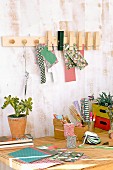 DIY rack with furniture knobs and wooden pegs above desk covered in craft utensils and potted plants