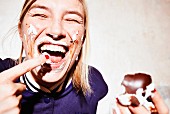Frau mit verschmiertem Gesicht isst Schokokuss