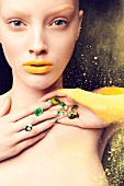 Junge Frau mit grünen Glassteinen, Hand und Arm gelb bemalt