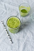 A green smoothie in a glass with striped straw