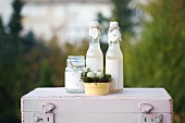 Easter arrangement: jar and bottles decorated with paper and Easter nest of quails' eggs on top of pink vintage suitcase