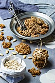 Vegan oat biscuits with almonds on a pewter plate with pastry tongs and baking ingredients