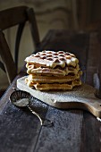 Waffles with icing sugar on a wooden board on a wooden bench