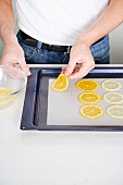 Slices of citrus fruit being placed on a baking tray