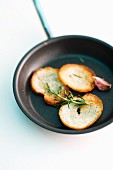 Bread chips with rosemary and garlic being roasted in a pan