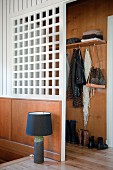 Table lamp with black lampshade on wooden floor in front of white partition screening cloakroom area at head of stairs