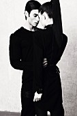 A young couple wearing black clothing embracing (black and white shot)