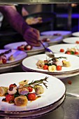 A chef in a restaurant kitchen plating up dishes