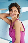 A young woman wearing a pink summer dress standing by a beach house