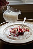 Milk being poured over porridge with figs and pomegranate seed