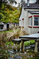 Rustic table and bench in autumnal garden outside white wooden house