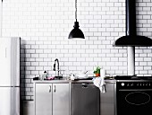 Moderne Küchenzeile in Edelstahl & Schwarz vor weisser Fliesenwand