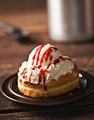 A glazed doughnut topped with vanilla ice cream and strawberry sauce