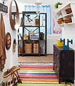 Hallway with metal locker, colourful striped rug and dark, open-fronted shelving unit at far end