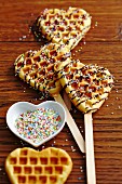 Sweet heart-shaped waffles on sticks with sugar pearls