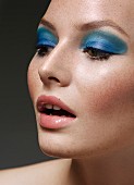 A young woman wearing blue eye shadow and nude lipstick