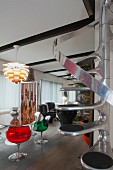 Retro Sitzplatz mit bunten Schalenstühlen aus transparentem Kunststoff unter Artischockenlampe, platzsparende Spindeltreppe