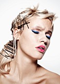 Blonde Frau mit blauem Eyeliner, pinkfarbenen Lippen und vielen Haarnadeln