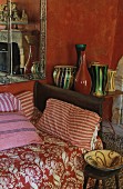 Sofa mit floral gemusterter Tagesdecke und gestreiften Kissen, seitlich auf Beistelltisch Vasensammlung
