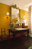 Schreibtisch als Waschtisch mit eingebautem Waschbecken und edler Goldrahmenspiegel an gelb getönter Wand
