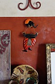 Far-Eastern wall decoration with elephant figurine above hand-crafted raffia basket against red-brown wall
