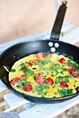 Omelette with tomatoes and herbs in a pan