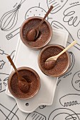 Three bowls of chocolate mousse with spoons